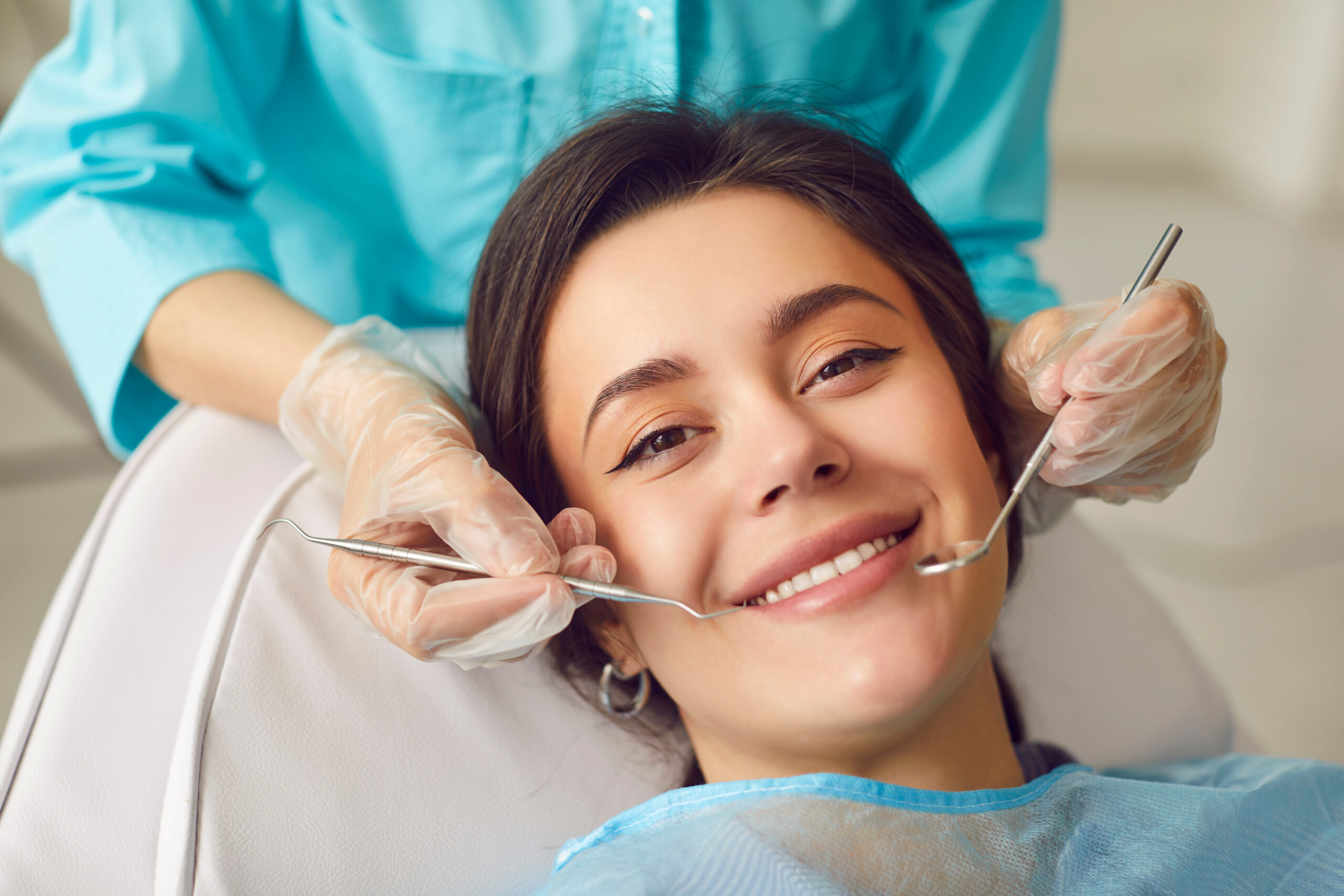 A young woman smiles in a dentists chair, face close-up