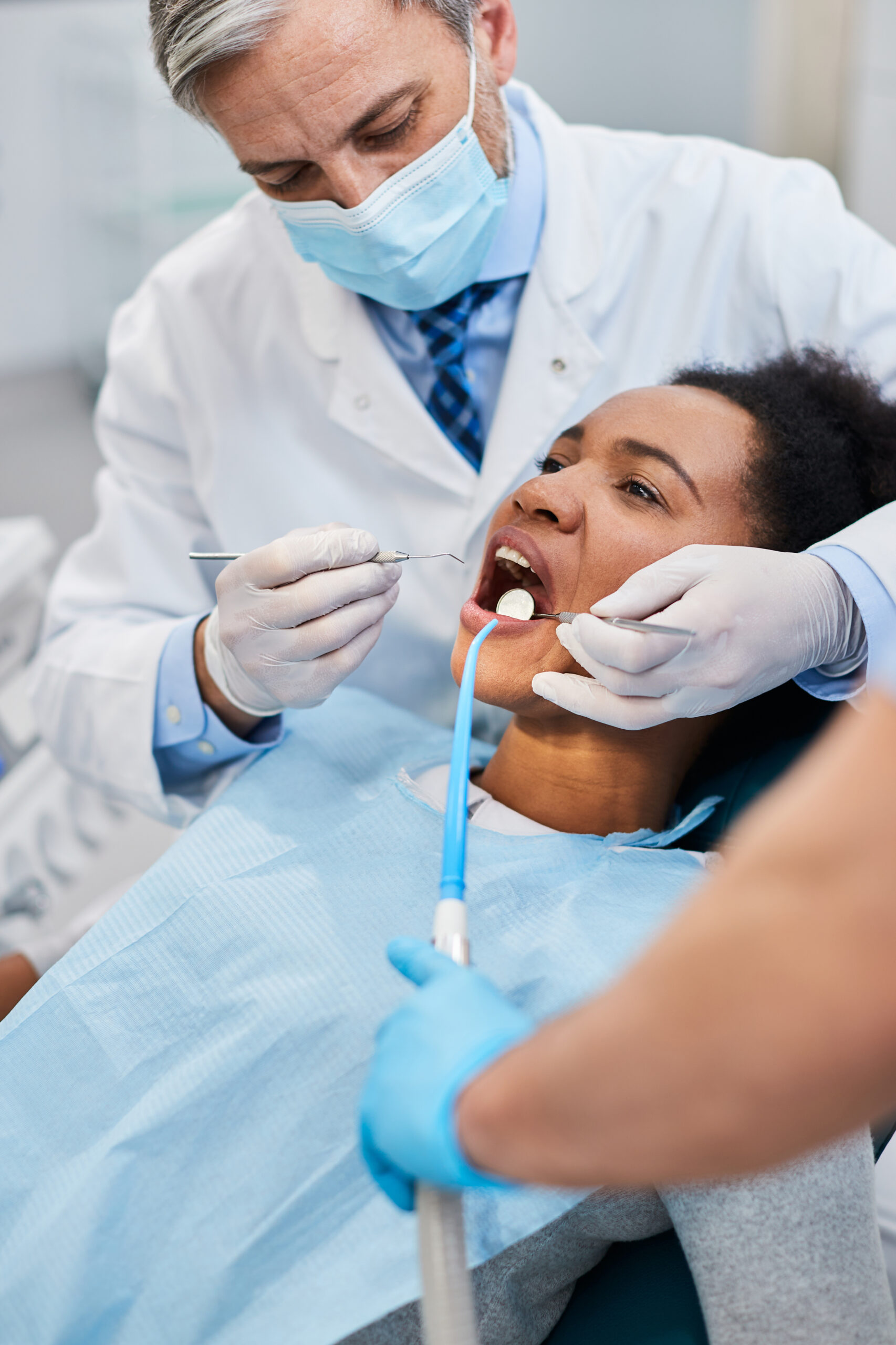 Black woman having her teeth checked by dentist during dental procedure at the clinic.
